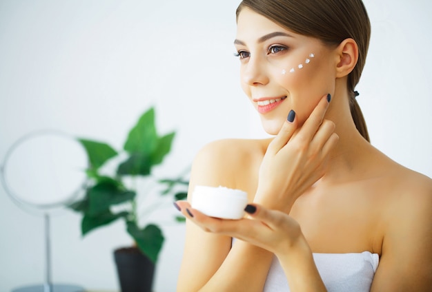 Bellezza e cura. Giovane donna con crema per viso nelle mani. Morni