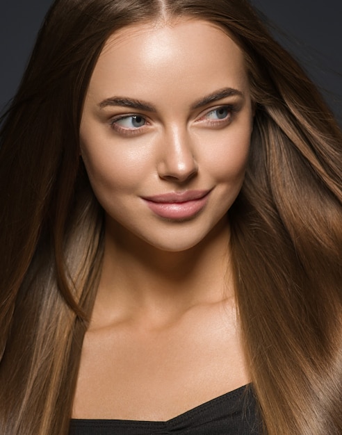 Bellezza liscia donna capelli lunghi bruna modello femminile trucco naturale bella ragazza sfondo scuro dark