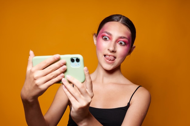 Bellezza moda femminile trucco luminoso in posa maglia nera con un telefono in mano vista ritagliata inalterata