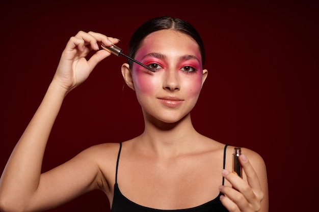 Bellezza moda trucco femminile emozioni cosmetici cura dei capelli mascara sfondo rosa inalterato