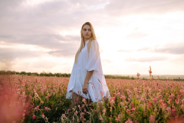 Bellezza ragazza romantica All'aperto al tramonto Giovane donna in abiti eleganti in posa nel campo fiorito