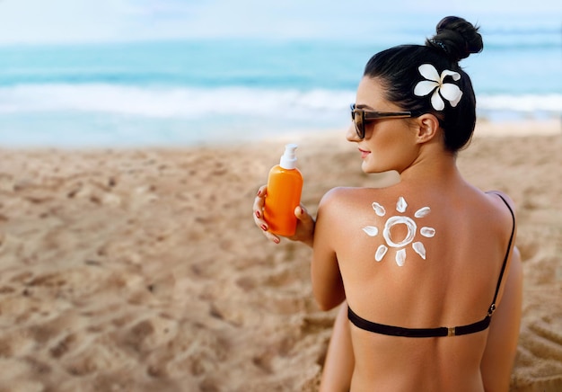 Bellezza Ritratto di donna splendida in bikini con il sole disegnato su una spalla in spiaggia