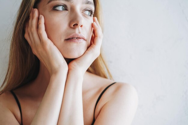 Bellezza ritratto di giovane donna con i capelli lunghi in abito nero elegante da sera in interni bianchi