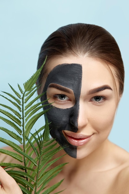 Bellezza ritratto donna cura della pelle salute maschera nera sfondo blu primo piano Maschera cosmetica