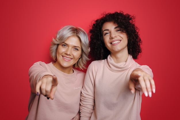 Bellezza viso modella donna dai capelli ricci che indica al gesto di invito della macchina fotografica per te bionda e...