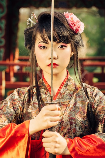 Bellissima geisha in kimono con spada samurai