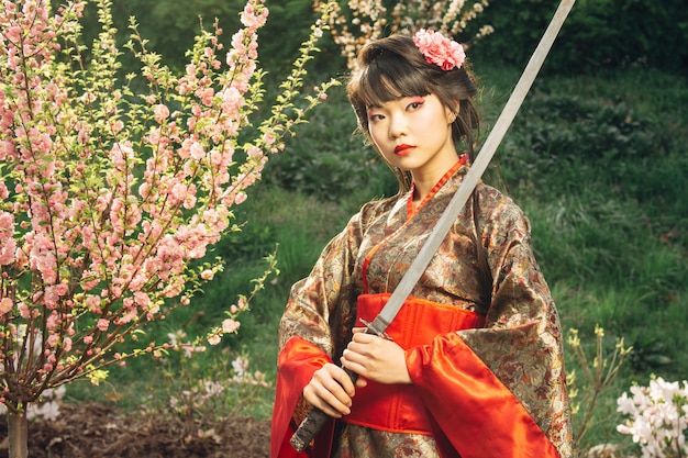 Bellissima geisha in kimono con spada samurai