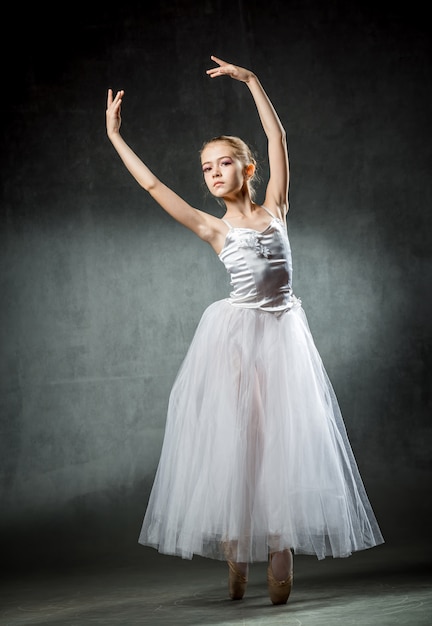 Bellissima giovane ballerina sta ballando in studio su un muro scuro Una piccola ballerina. Ballerino classico.