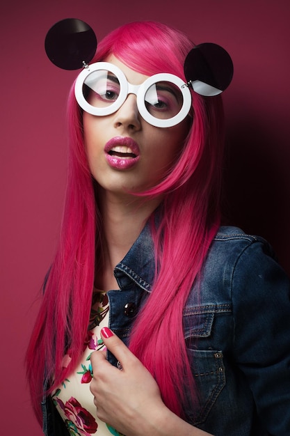 Bellissima modella con capelli rosa e trucco che indossa grandi occhiali da sole