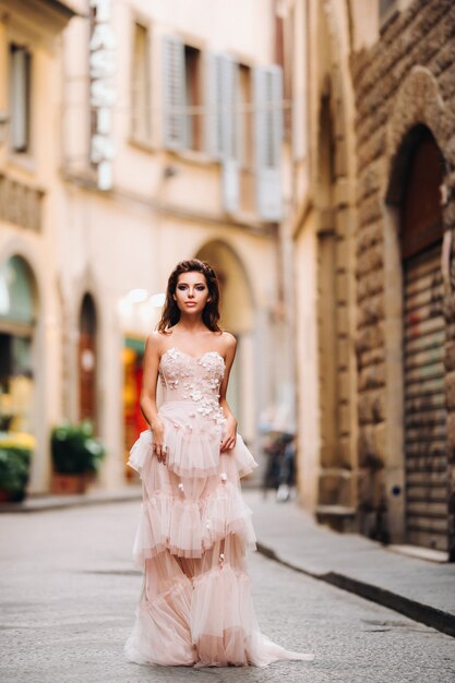 Bellissima modella elegante ragazza in abito da sposa rosa fotografata a Firenze, con in mano un insolito bouquet, modella sposa con un bouquet in mano, servizio fotografico della sposa a Firenze.