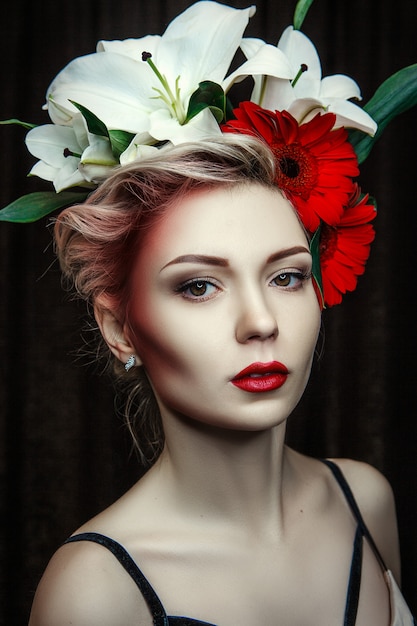 Bellissima modella posa con trucco creativo e fiori intorno al viso
