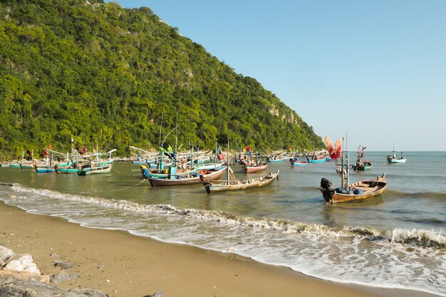 Bellissima spiaggia con rocce e barche blu del mare del pescatore