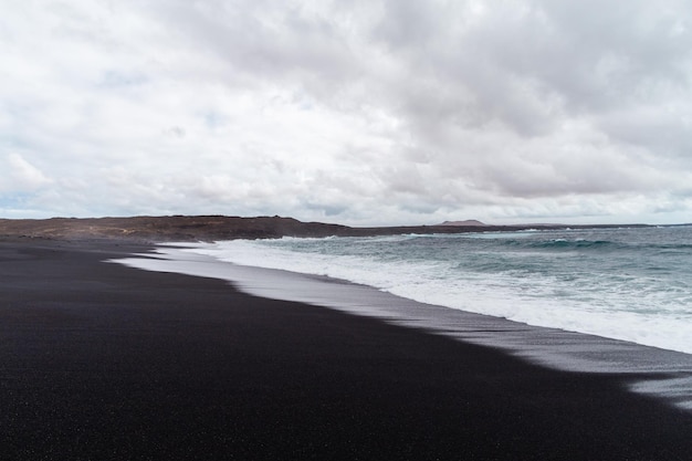 Bellissima spiaggia sull'isola di Lanzarote Spiaggia sabbiosa circondata da montagne vulcaniche Oceano Atlantico e meravigliosa spiaggia Lanzarote Isole Canarie