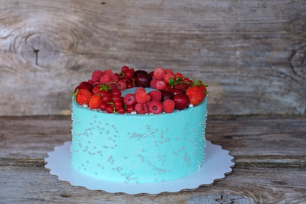 Bellissima torta fatta in casa con crema di formaggio bianco e blu e frutti di bosco di lamponi e ribes