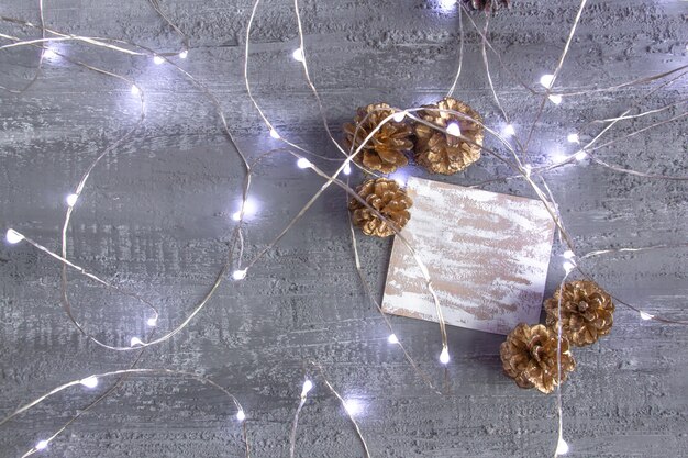 Bellissime decorazioni natalizie in tonalità oro argento pigne luci di capodanno e biglietto bianco su un concre...