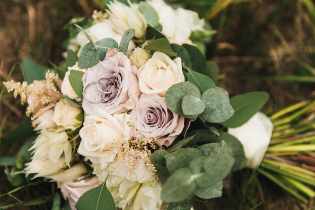 Bellissime fedi nuziali sul bouquet della sposa in colori pastello