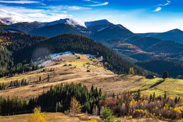 Bellissime foreste colorate che coprono le montagne dei Carpazi e un piccolo villaggio sullo sfondo di un caldo cielo autunnale