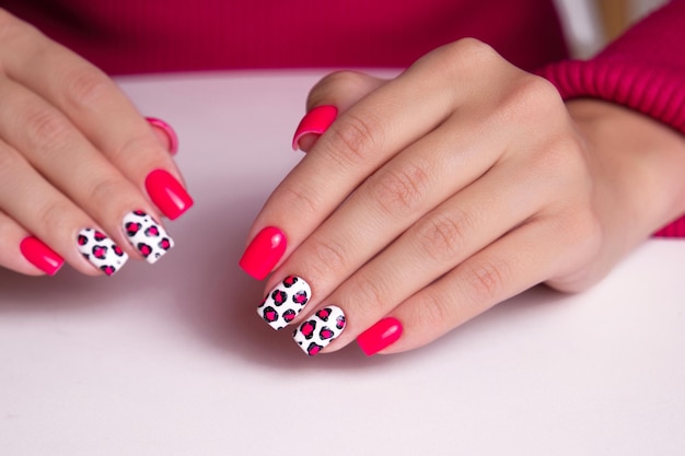 Bellissime mani femminili con unghie a manicure rosa disegno a stampa di leopardo su sfondo bianco