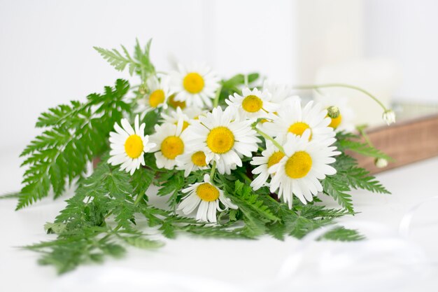 Bellissime margherite e altri fiori su un tavolo bianco.