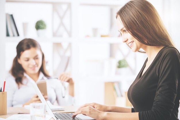 Bellissime ragazze che usano il computer portatile sul posto di lavoro