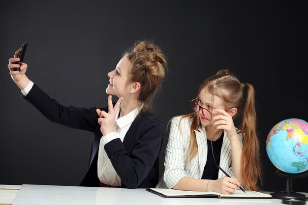 Bellissimi amici di scuola divertenti che fanno selfie nel corridoio della scuola sul telefono