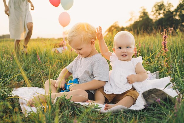 Bellissimi bambini che giocano sulla natura all'aperto Fratello e sorella in estate al tramonto Bambina e bambino stanno facendo un picnic su sfondo verde natura Foto di valori familiari infanzia felice