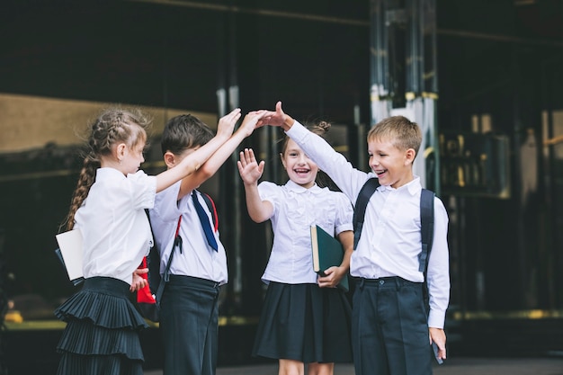 Bellissimi bambini in età scolare attivi e felici sullo sfondo della scuola in uniforme