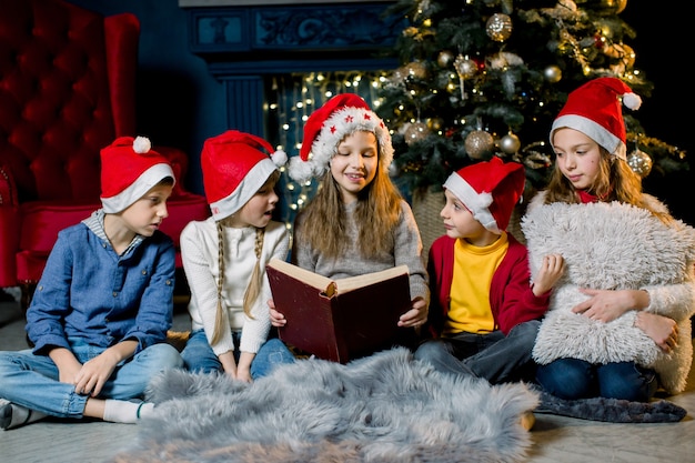 Bellissimi bambini piccoli leggono un libro con storie di Natale