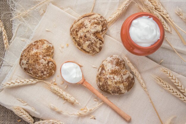 Bellissimi biscotti di pan di zenzero a forma di cuore sono disposti con panna acida Deliziosi biscotti