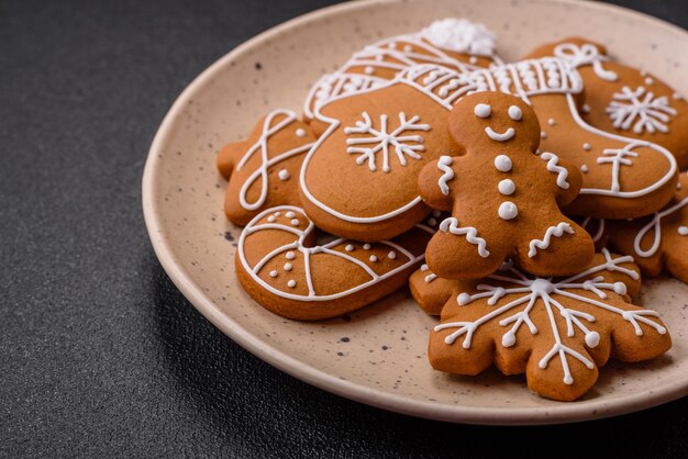 Bellissimi biscotti di pan di zenzero di Natale di diversi colori su un piatto di ceramica