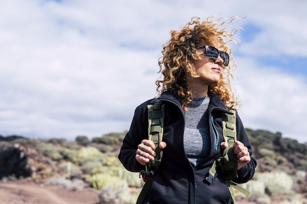 Bellissimi capelli ricci donna caucasica di mezza età con zaino in attività di trekking all'aperto