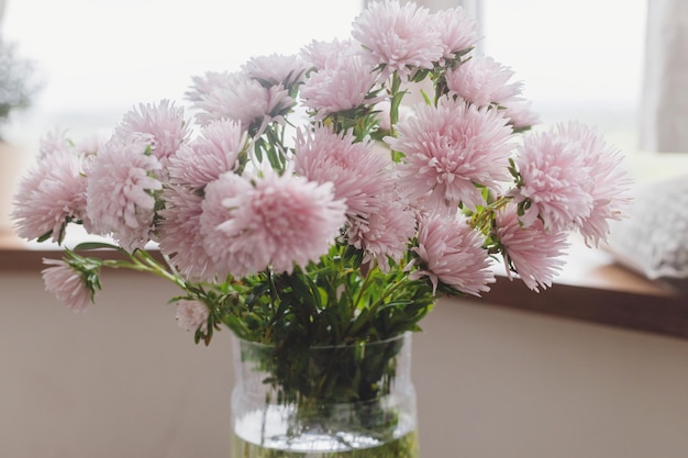 Bellissimi fiori autunnali in vaso moderno su sfondo rustico in legno Fiori di aster rosa da vicino