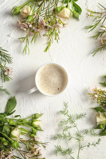 Bellissimi fiori con una tazza di caffè su sfondo chiaro con texture