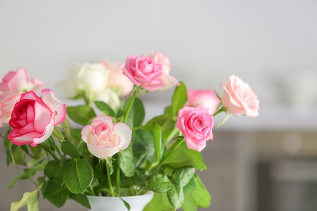 Bellissimi fiori di rosa in vaso su offuscata