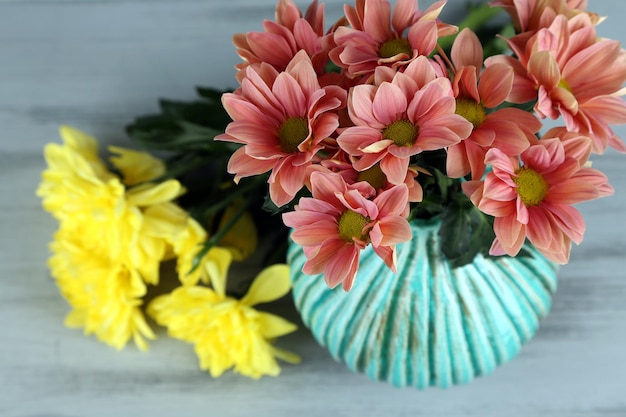 Bellissimi fiori in vaso sulla tavola di legno su sfondo chiaro