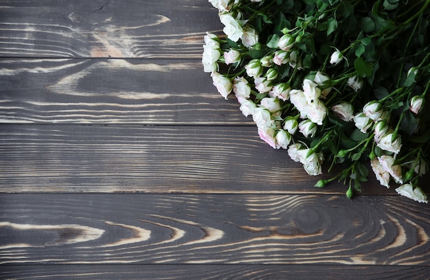 Bellissimi fiori su fondo in legno. Mazzo di rose. Perfetto piatto disteso con petali. Cartolina di festa della madre felice. Saluto per la giornata internazionale della donna. Idea elegante per pubblicità o promozione.