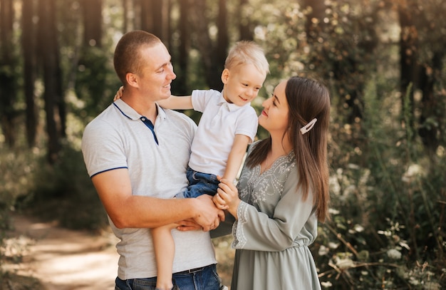 Bellissimi genitori di famiglia e un giovane figlio in un campo di grano. Mamma, papà e bambino insieme. Famiglia felice, i genitori abbracciano il loro figlioletto