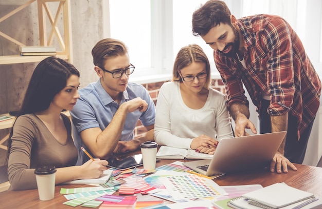 Bellissimi giovani designer stanno usando un laptop per discutere idee e prendere appunti mentre lavorano in ufficio