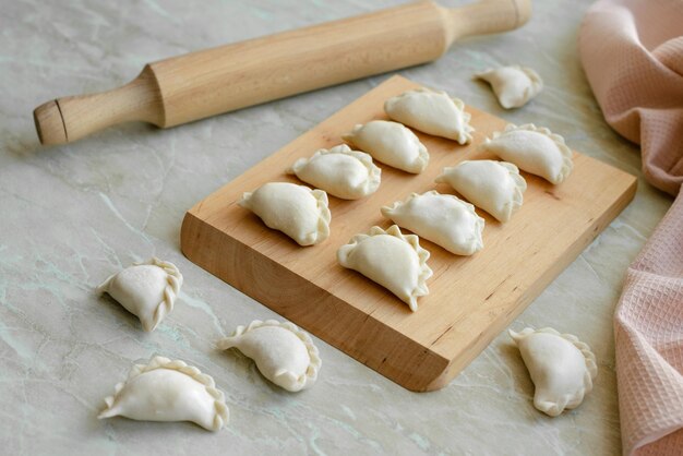 Bellissimi gnocchi ripieni crudi su un tagliere di legno Deliziosi fast food