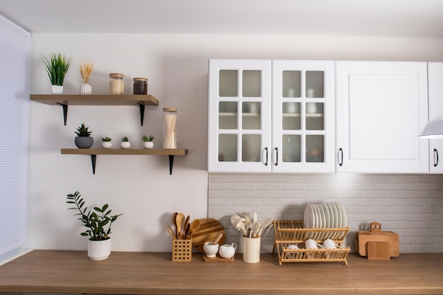 Bellissimi interni moderni della cucina bianca parte del muro con mensole con fiori e utensili da cucina il concetto di minimalismo