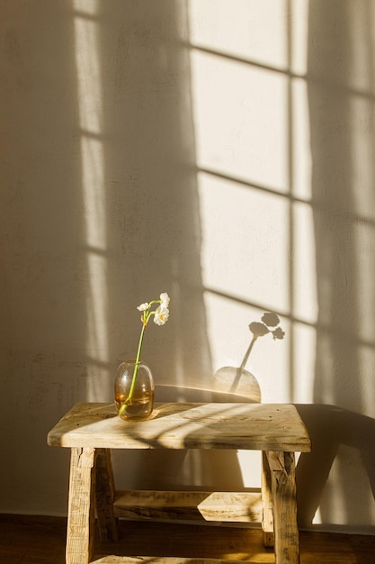 Bellissimi narcisi in vaso su panca in legno rustico sullo sfondo di una camera moderna alla luce del sole Elegante arredamento floreale per la casa casa colonica design della camera da letto Fiori primaverili