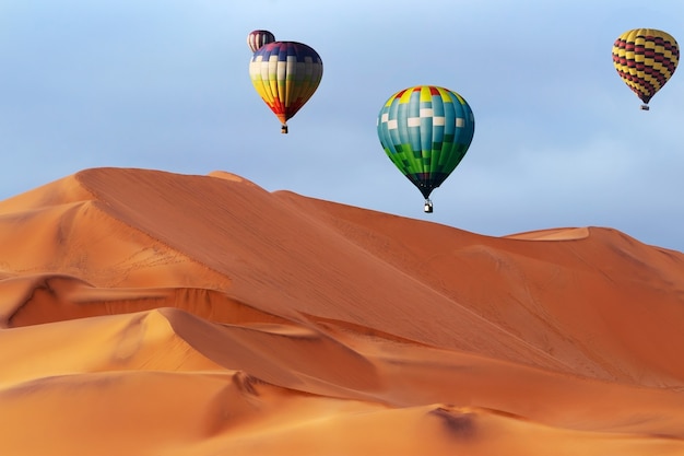 Bellissimi palloncini colorati ad aria calda e nuvole drammatiche sulle dune di sabbia nel deserto del Namibb