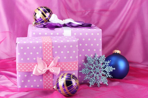 Bellissimi regali, palle di Natale e fiocco di neve su una superficie rosa