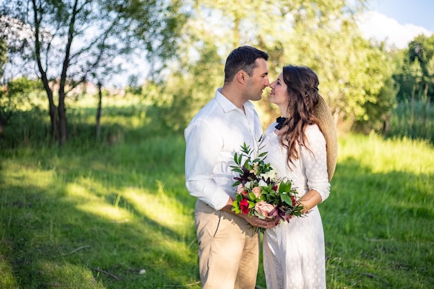 Bellissimi sposini stanno su un prato verde e baciano un matrimonio in stile rustico