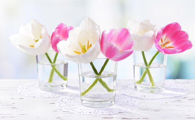 Bellissimi tulipani in secchio in vaso sul tavolo su sfondo chiaro