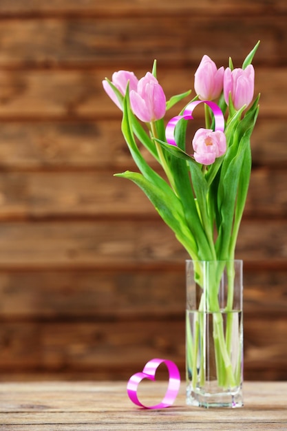 Bellissimi tulipani rosa con cuore decorativo su fondo in legno