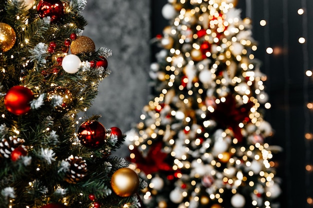 Bellissimo albero di Natale con decorazioni festose rosso oro contro luci sfocate su sfondo closeup