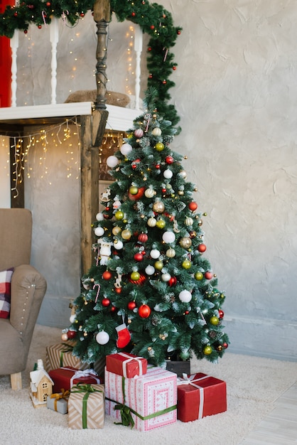 Bellissimo albero di Natale con palline rosse, bianche e oro e regali sotto di esso nel soggiorno della casa o dell'appartamento