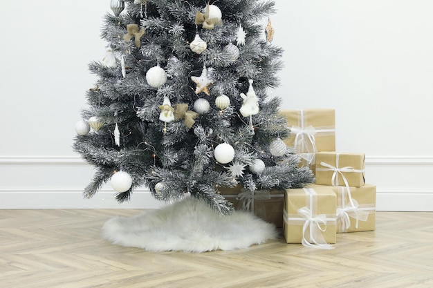Bellissimo albero di Natale decorato con gonna e scatole regalo in camera