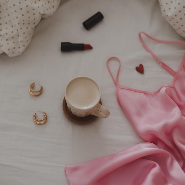 Bellissimo arrangiamento femminile flatlay con tazza da caffè in lingerie, gioielli e accessori
